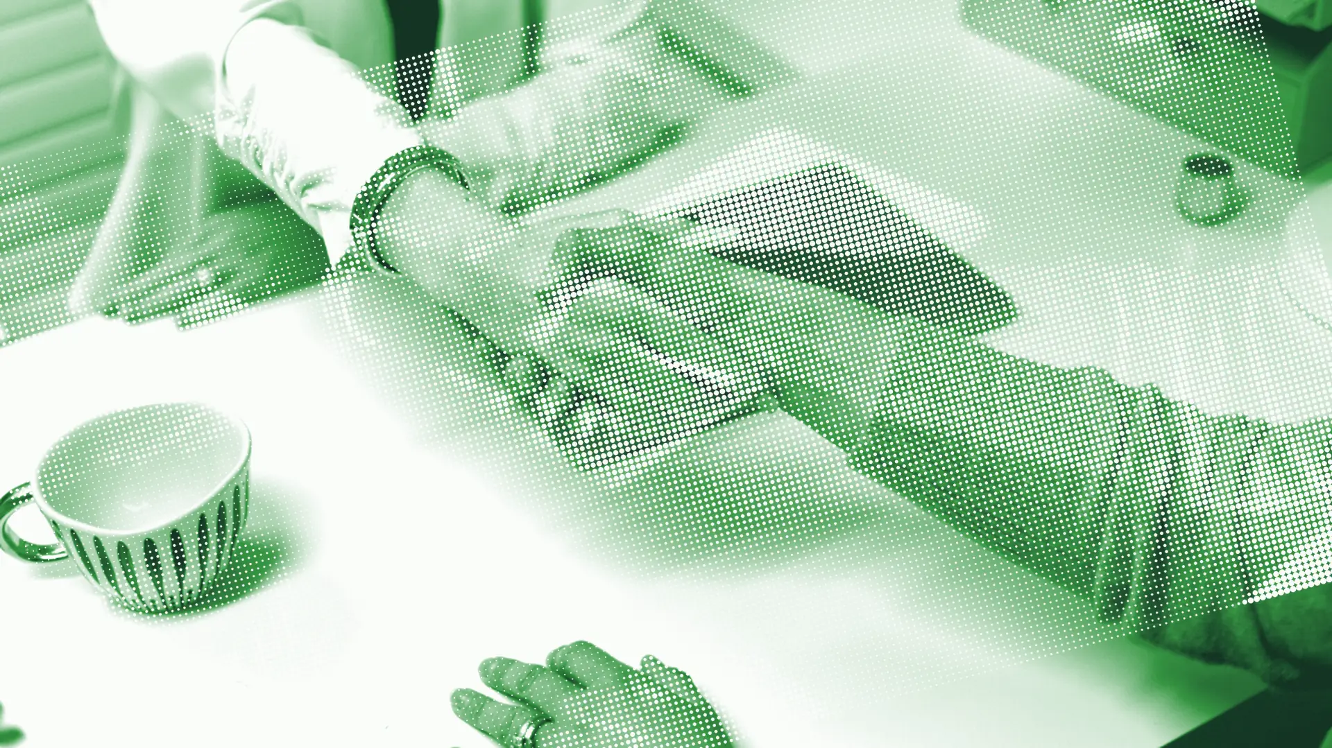 Two people shaking hands across a table.